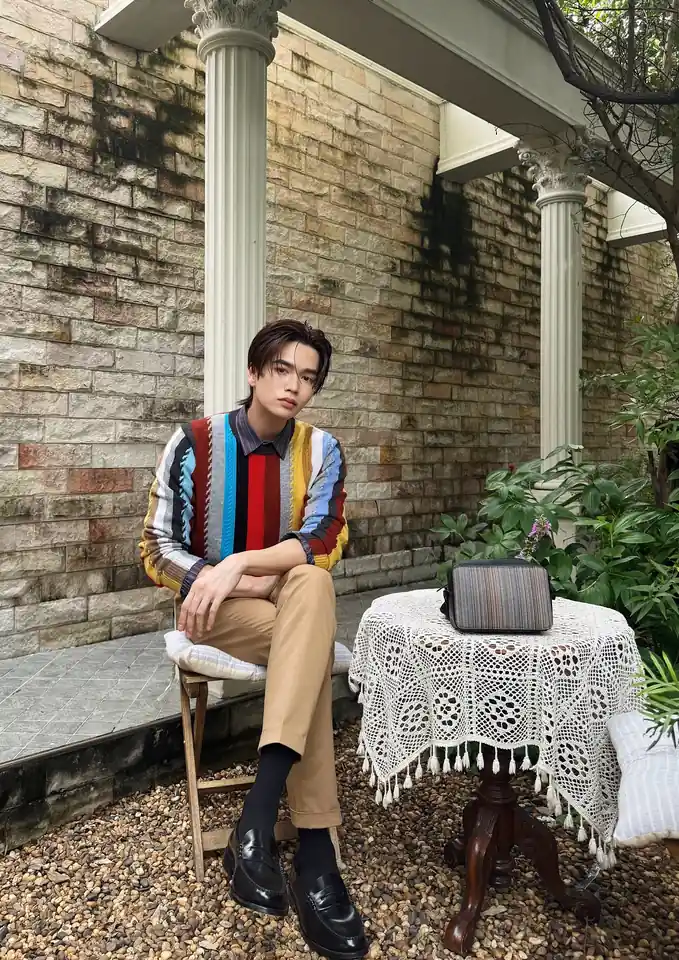 มาร์ค จิรันธนิน นั่งหน้ากำแพงอิฐในชุดสีสันสดใส